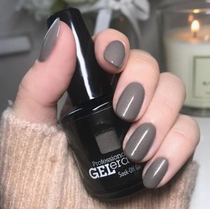 Hand with painted gel nails holding nail polish bottle